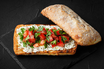 wholegraine ciabatta sandwich with sliced tomatoes, goat cheese, parsley. top view