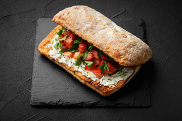 wholegraine ciabatta sandwich with sliced tomatoes, goat cheese, parsley. top view