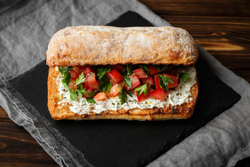 wholegraine ciabatta sandwich with sliced tomatoes, goat cheese, parsley. top view