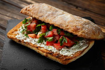 wholegraine ciabatta sandwich with sliced tomatoes, goat cheese, parsley. top view