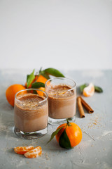 Glass of hot tangerine orange cocoa or chocolate decorated citrus peel on gray background with copy space.Vertical orientation