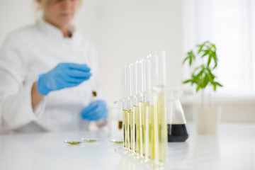 Scientist working with pharmaceutical cbd oil in a laboratory with a glass equipment