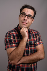 Handsome Persian man wearing eyeglasses against gray background