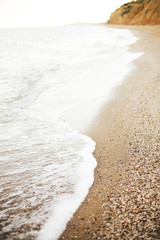 Beautiful sea waves foam closeup and sandy beach with seashells on tropical island. Waves in ocean bay or lagoon. Tranquil calm moment. Summer vacation. Copy space