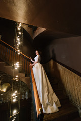 the bride in a wedding dress stands on a wooden staircase