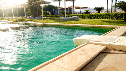 Closeup image of luxurious villa with outdoor swimming pool against beautiful sunset sky