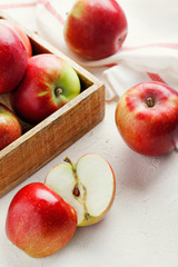 Harvest fresh ripe red apples in a wooden box on a white background top view.Organic vegetarian produce.Vertical orientation