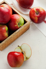 Harvest fresh ripe red apples in a wooden box on a white background top view.Organic vegetarian produce.Vertical orientation