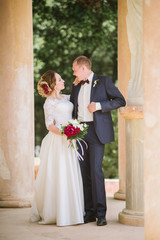 The groom in a suit and the bride in a wedding dress are walking in the park