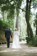 Fototapeta na wymiar The groom in a suit and the bride in a wedding dress are walking in the park