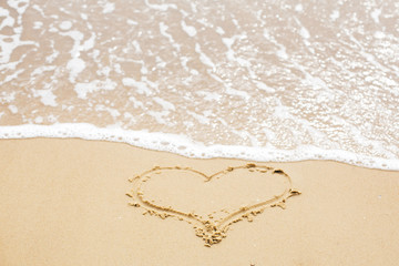 Heart sign on beach. Heart symbol on sandy beach and sea waves with foam. Love and hello summer concept. Vacation, relax and travel. Copy space. Valentine day gift