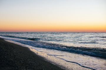 Beautiful sea waves foam closeup and sandy beach with seashells in sunrise light on tropical island. Waves in ocean at sunset. Tranquil calm moment. Summer vacation. Copy space