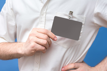 Man showing badge card, blue background, men's hand, badge, man in white shirt, close up, copy space, for advertising, slogan