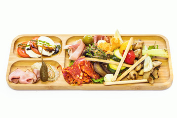 Snacks on a wooden plateau. Ham, mozzarella, olives and other vegetables. Restaurant serving