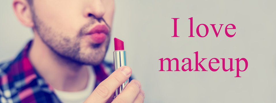 White metrosexual, man holding red lipstick in his hand close to face, on camera, lettering, I love makeup, front view, close up,