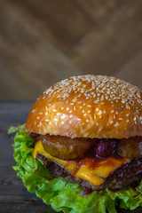 Burger, hamburger sandwich with cutlet of minced meat, melted cheese, berry cherry and pear. Top view on a wooden backdrop and light wooden board.