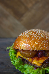 Burger, hamburger sandwich with cutlet of minced meat, melted cheese, berry cherry and pear. Top view on a wooden backdrop and light wooden board.