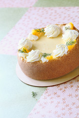 Fototapeta na wymiar Orange Cheesecake decorated with orange slices and whipped cream roses, on a wooden board, on light floral background.