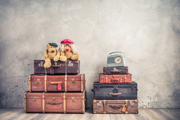 Vintage outdated trunks luggage, old antique leather valises,  pair of Teddy Bear toys and classic portable radio front concrete wall background. Retro style filtered photo