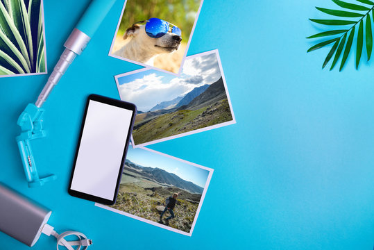 Smartphone with blank screen, flyers, photos on blue background. Mockup, flat lay Vacation concept