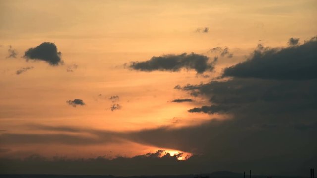 Superzoom plan timelapse sunset through sunset clouds in orange tones. Low key