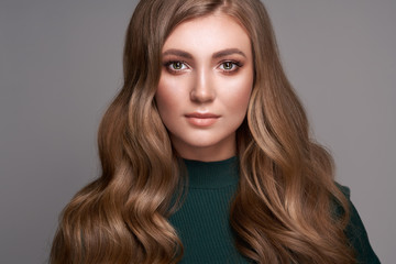 Fototapeta premium Brunette Girl with Long Healthy and Shiny Curly Hair. Care and Beauty Hair products. Beautiful Model Woman with Wavy Hairstyle. Perfect Make-Up