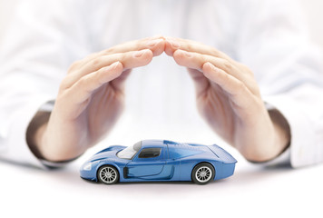 Car insurance concept with blue car toy covered by hands