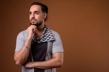 Young bearded Indian man against brown background