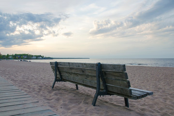 Naklejka na ściany i meble Rear view of an wooden bench on a deserted sandy beach