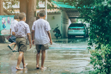Boy students leave the classroom to walk on the street after heavy rain in the school.