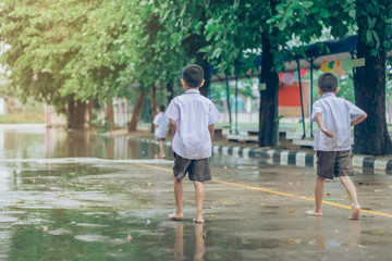 Boy students leave the classroom to walk on the street after heavy rain in the school.