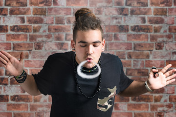 Vaper Smoke outdoor electronic cigarette near the brick wall. Young man smoking big cloud of steam