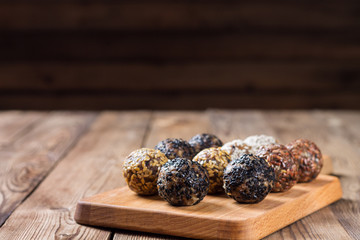 A group of energy balls lying on parchment paper on a kitchen Board. Blurred wooden background. The concept of healthy eating.