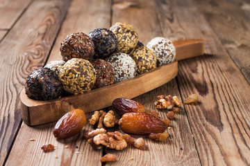 A group of energy balls lying on a wooden tray with a handle. Blurred wooden background. Organic natural food.