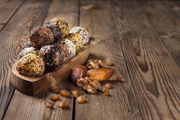 A group of energy balls lying on a wooden tray with a handle. Blurred wooden background. Organic natural food.