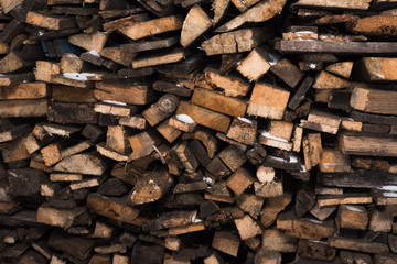 Chipped wood in the snow. Woodpile (stack of wood) on a rusty background. Firewood background
