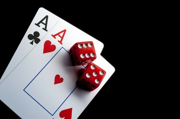 Close-up - Two aces, playing cards and red gaming dices on black table.