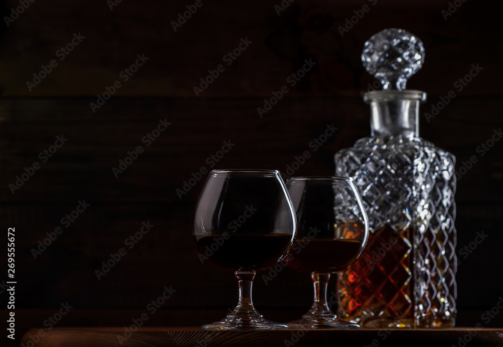 Wall mural brandy or cognac in glasses and a decanter on a brown wooden background