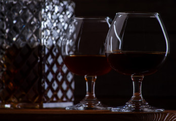 Brandy or cognac in glasses and a decanter on a brown wooden background