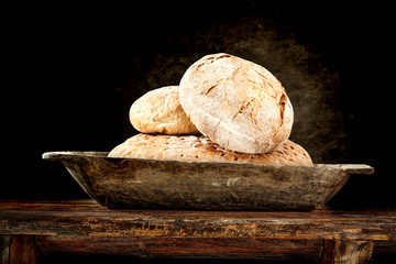 Fresh bread on wooden plate and dark wall of free space for your decoration. 
