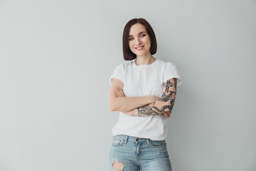 Stylish tattooed woman on light background