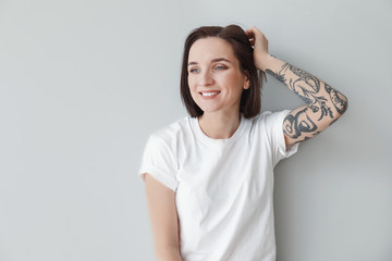 Stylish tattooed woman on light background