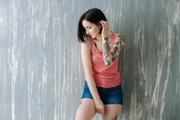 Obraz premium Beautiful tattooed woman near grunge wall