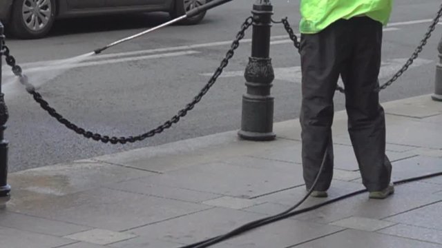 Washing the sidewalk with a jet of water. Janitor's work, cleaning of streets. Super slow motion 1000 fps