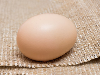 Fresh chicken egg lays on a rough sack_