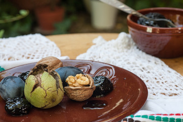 Fresh and dried prunes on plate.