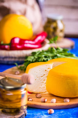 Cheese wheel on a wooden board. Blurred background.