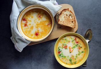 creamy salmon soup in a saucepan and yellow bowl. bread on a plate