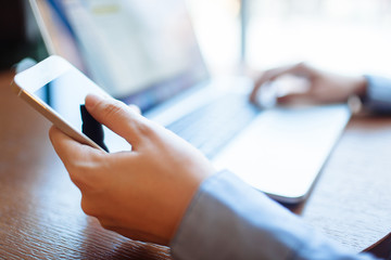 Young woman working in a cafe, keyboard on a laptop computer. Blond student working for netbook after lectures at the university.