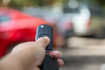 Business woman presses a button on the car remote control key against blur car modern lifestyle concept